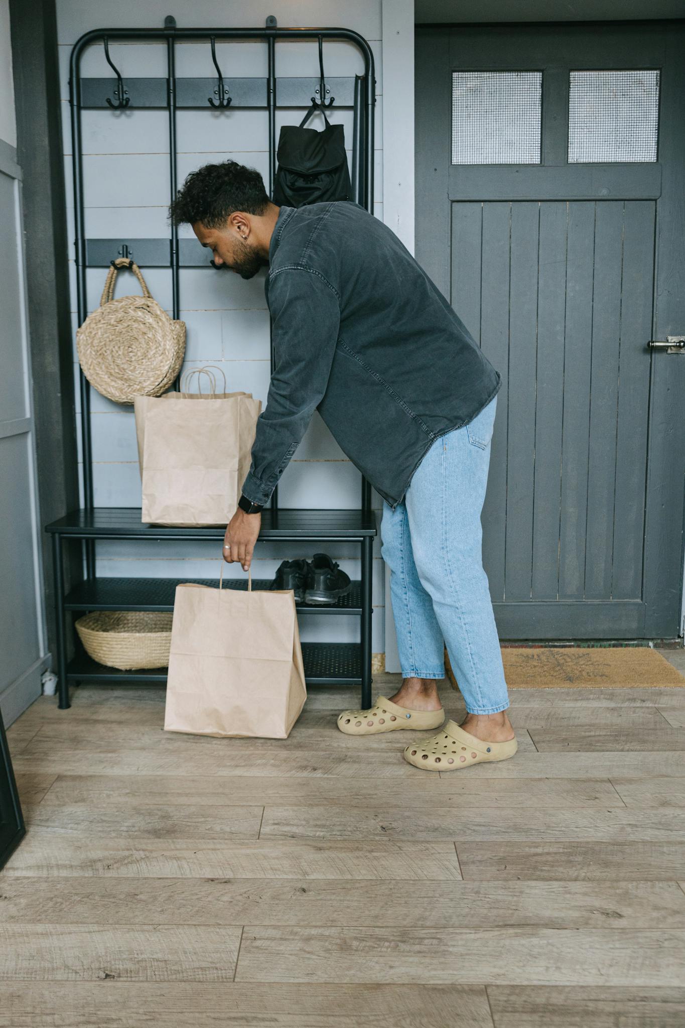 Person arranging shopping bags in a stylish apartment hallway.