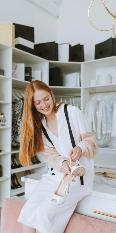 Young woman joyfully holding shoes in a modern boutique. Chic and stylish atmosphere.